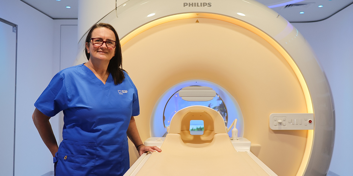 Angela Borella, MRI Network Supervisor at Monash Health, stands next to an MRI machine.