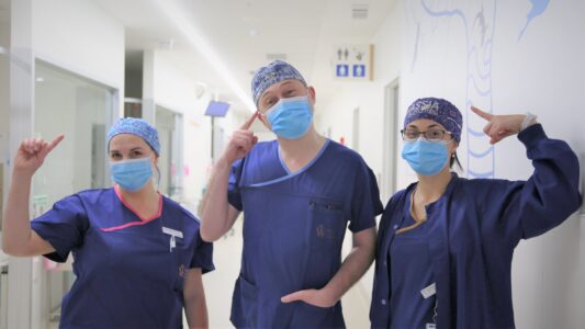 Photo of three clinical employees wearing their clue patterned cloth hats in the ward.