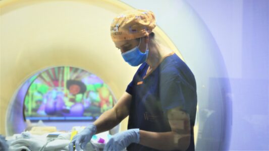 Photo of Dr Jackson wearing a yellow patterned cloth hat in magnetic resonance imaging (MRI).
