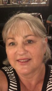 A lady with short light hair smiles to camera